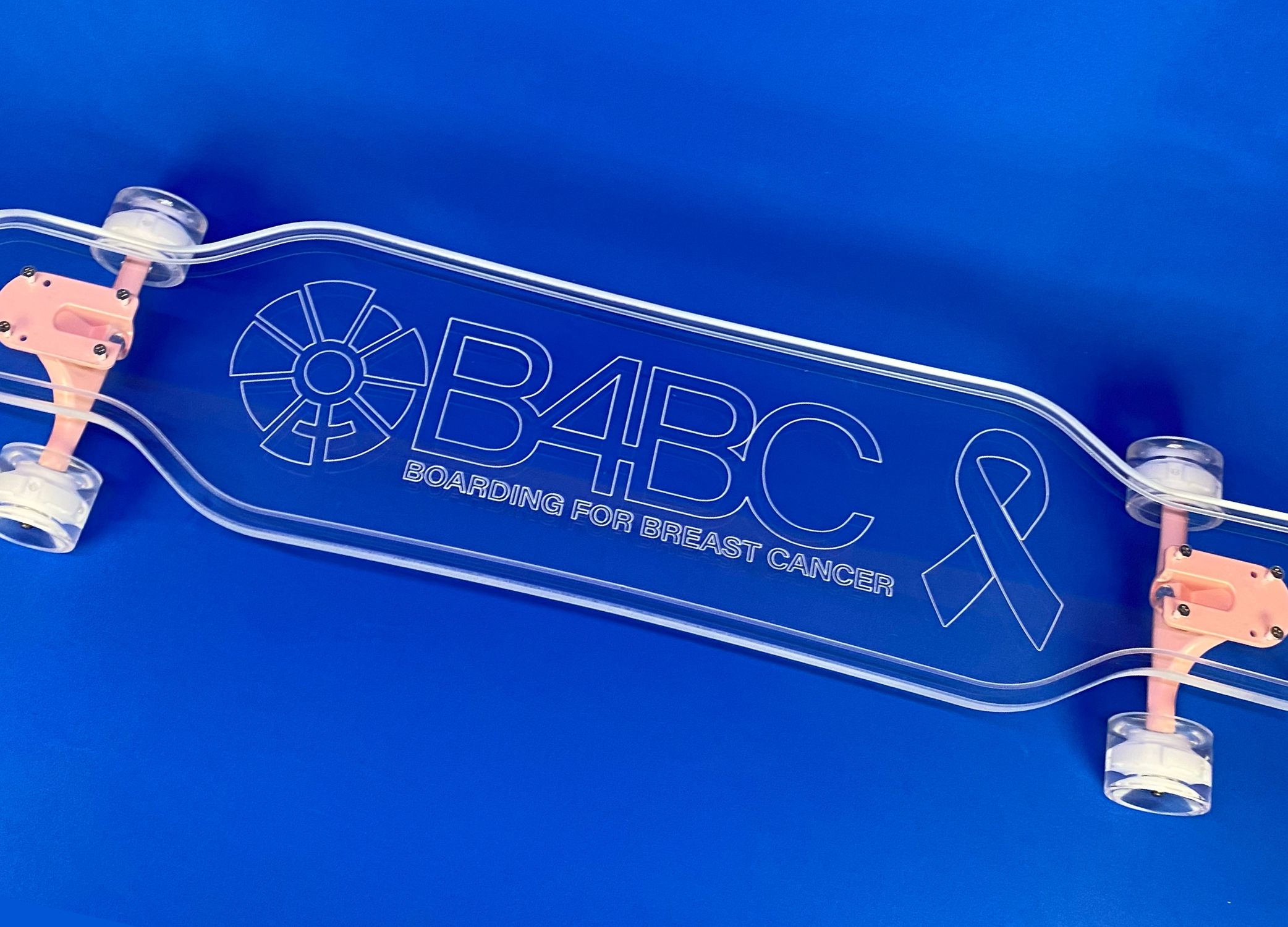 Clear B4BC longboard that has the non-profit organizations logo on it.